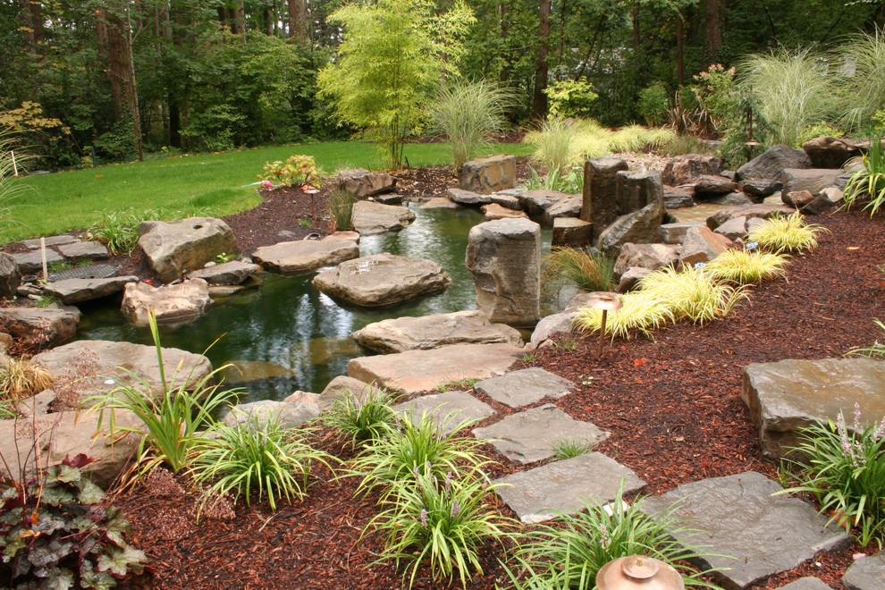 This is an example of a large world-inspired back formal garden in Portland with a water feature and natural stone paving.