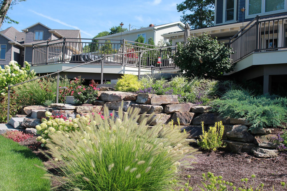 На фото: большой участок и сад на заднем дворе в стиле кантри с подпорной стенкой и мульчированием
