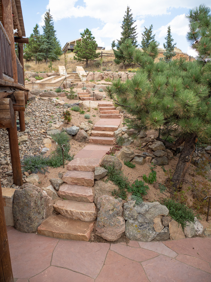 Photo of a large rustic drought-tolerant and shade backyard stone retaining wall landscape in Other for summer.
