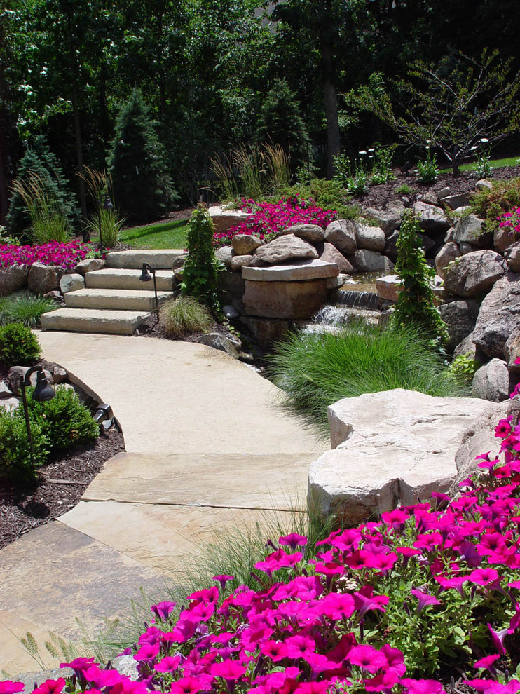 Imagen de camino de jardín clásico grande en patio trasero con exposición total al sol y adoquines de piedra natural