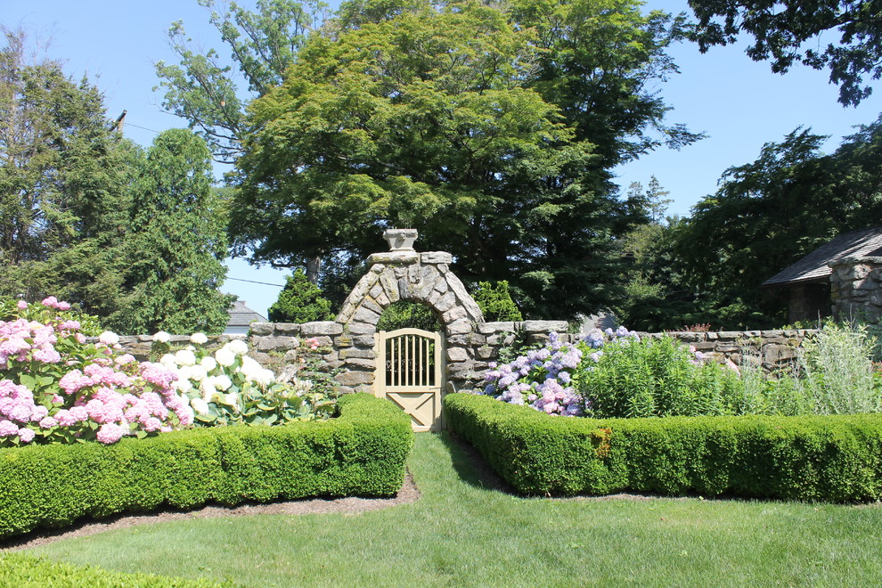 Cette photo montre un jardin arrière chic de taille moyenne avec une exposition partiellement ombragée et des pavés en pierre naturelle.