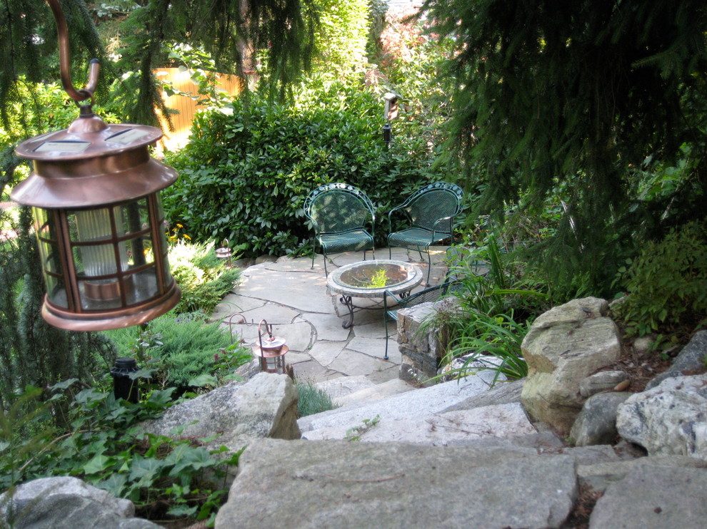 Идея дизайна: участок и сад на склоне в стиле кантри с местом для костра, полуденной тенью и покрытием из каменной брусчатки