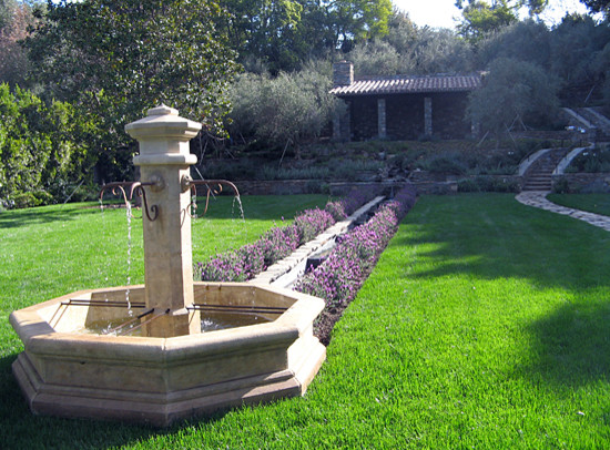 Foto di un grande giardino mediterraneo esposto a mezz'ombra dietro casa con fontane e pavimentazioni in pietra naturale
