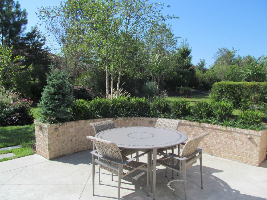 This is an example of a large traditional back patio in Other with natural stone paving.