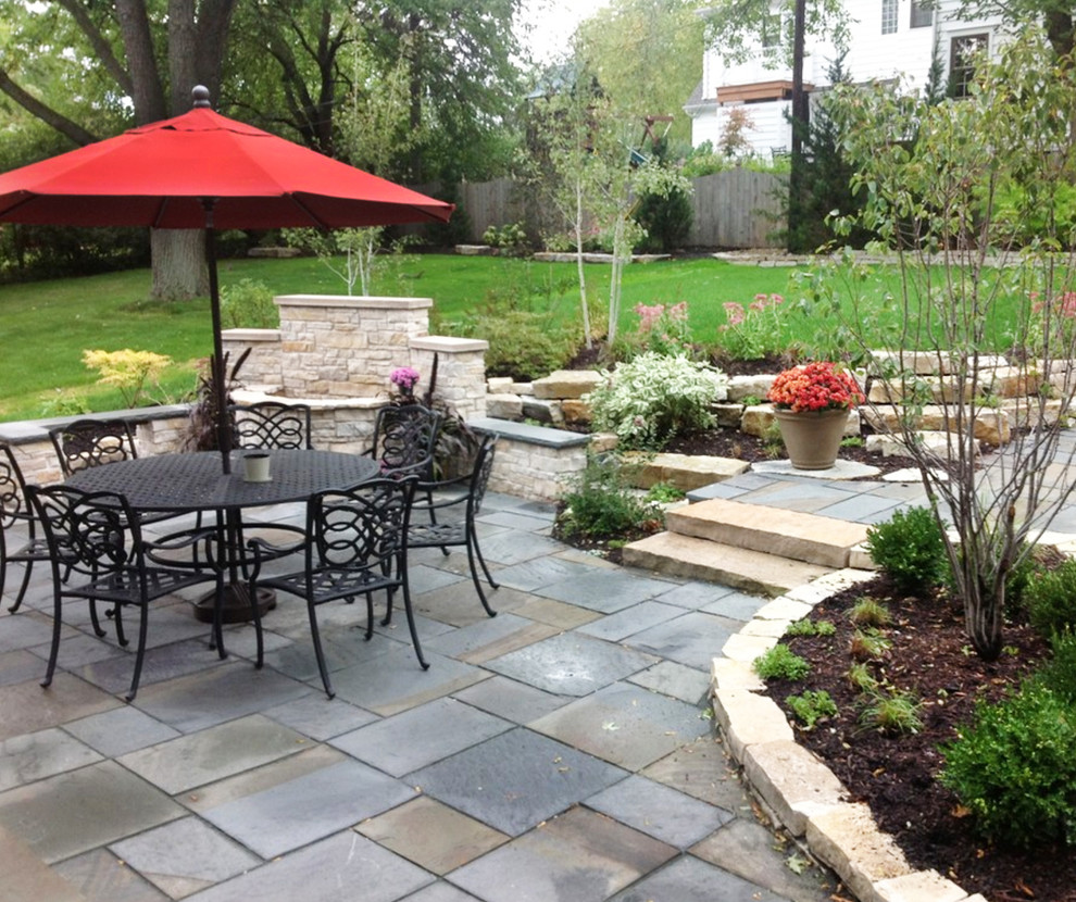 Ejemplo de jardín clásico de tamaño medio en patio trasero con adoquines de piedra natural, brasero y exposición total al sol