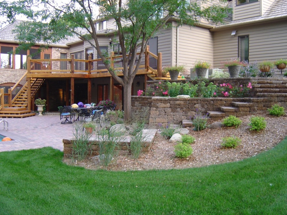 This is an example of a classic formal partial sun garden for summer in Other with a retaining wall and concrete paving.