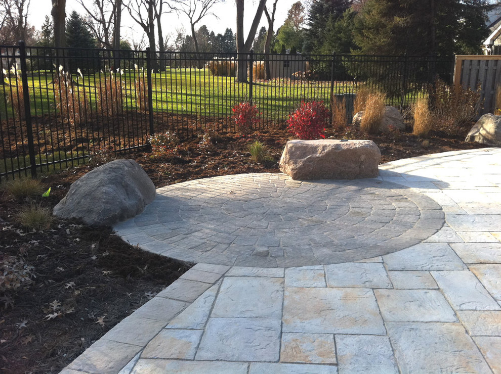 This is an example of a large traditional back partial sun garden in Other with natural stone paving.