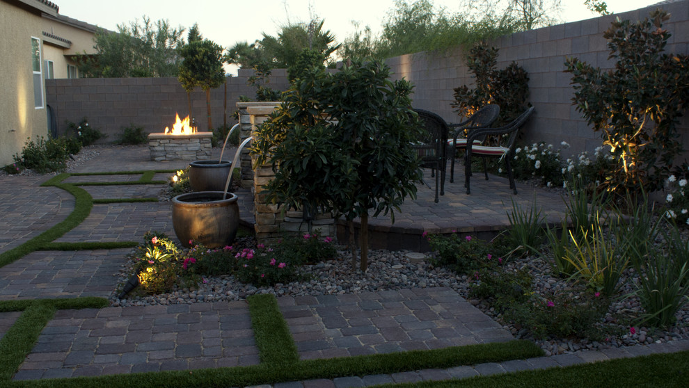 Photo of a mid-sized traditional drought-tolerant and full sun backyard concrete paver landscaping in Las Vegas.