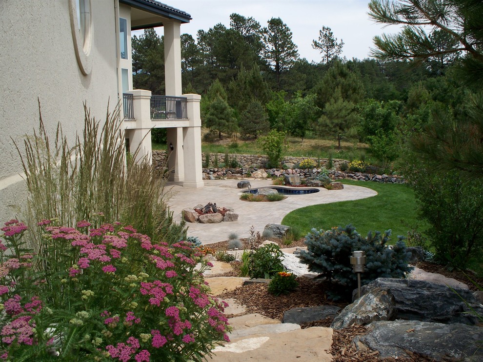 Aménagement d'un grand jardin arrière classique avec des pavés en pierre naturelle et un foyer extérieur.