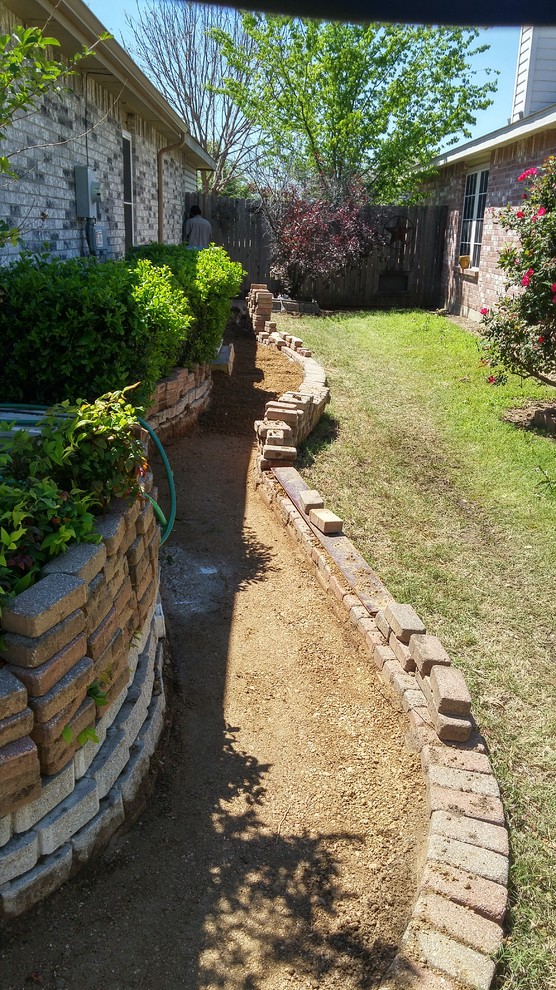 Aménagement d'un jardin latéral contemporain de taille moyenne avec un mur de soutènement, une exposition ensoleillée et des pavés en brique.