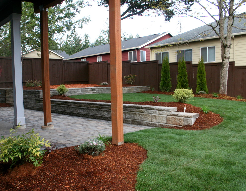 Imagen de jardín clásico grande en patio trasero con muro de contención y adoquines de hormigón