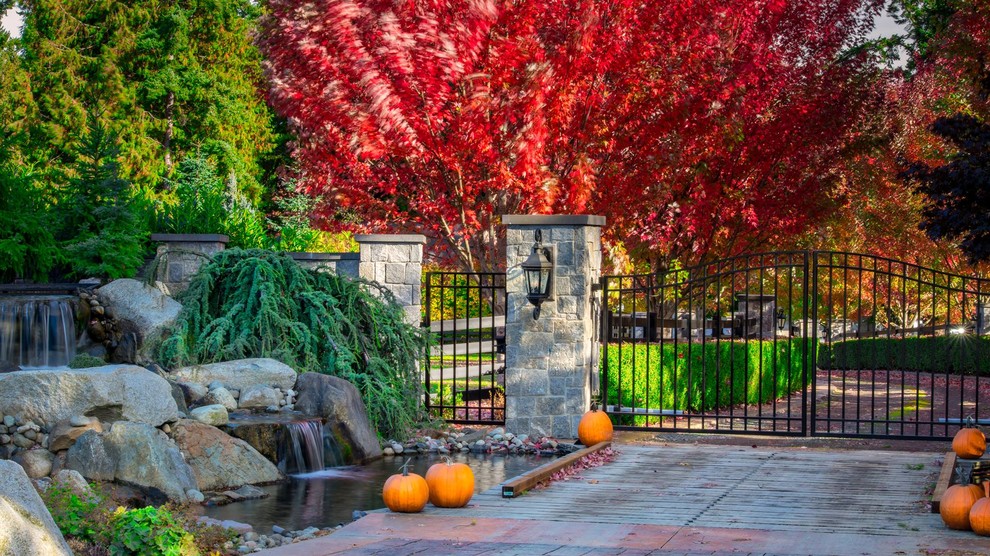 Foto di un ampio vialetto d'ingresso esposto in pieno sole davanti casa in autunno con fontane e pavimentazioni in pietra naturale