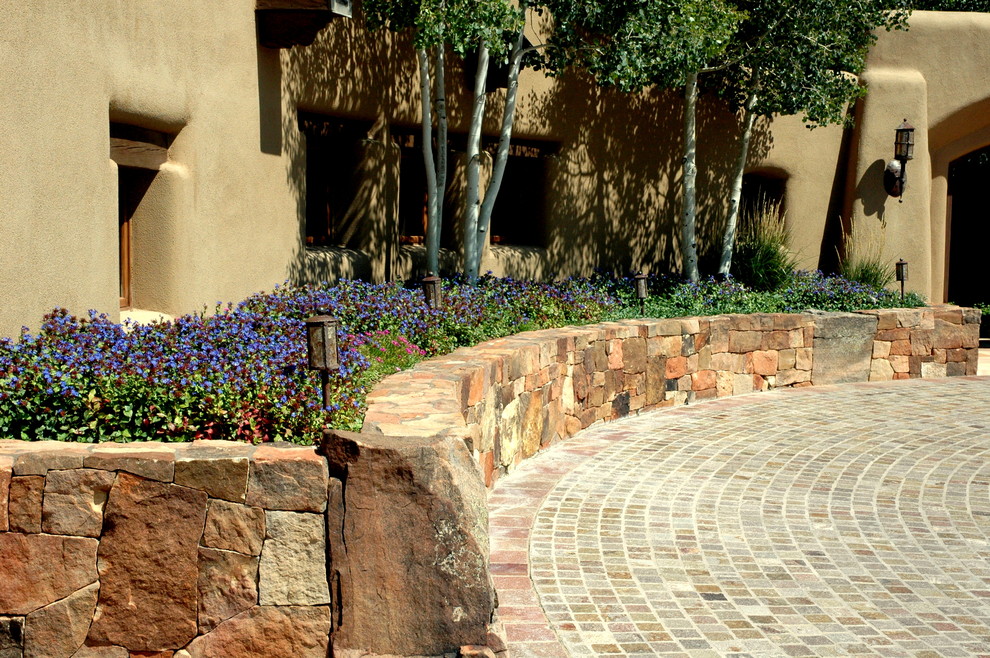 На фото: солнечный, летний участок и сад среднего размера на переднем дворе в современном стиле с подъездной дорогой, подпорной стенкой, хорошей освещенностью и покрытием из каменной брусчатки