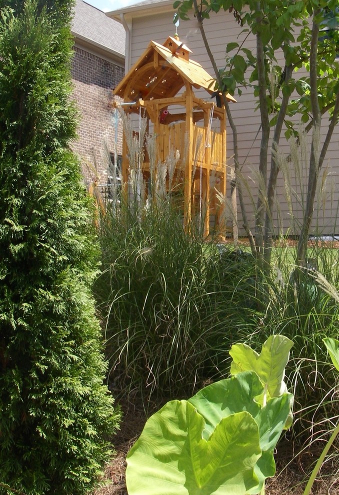 Foto di un giardino tropicale esposto in pieno sole di medie dimensioni e dietro casa in estate con uno spazio giochi