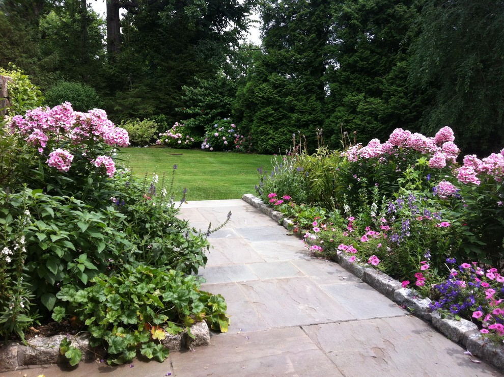 This is an example of a medium sized traditional back formal partial sun garden in New York with concrete paving and a retaining wall.
