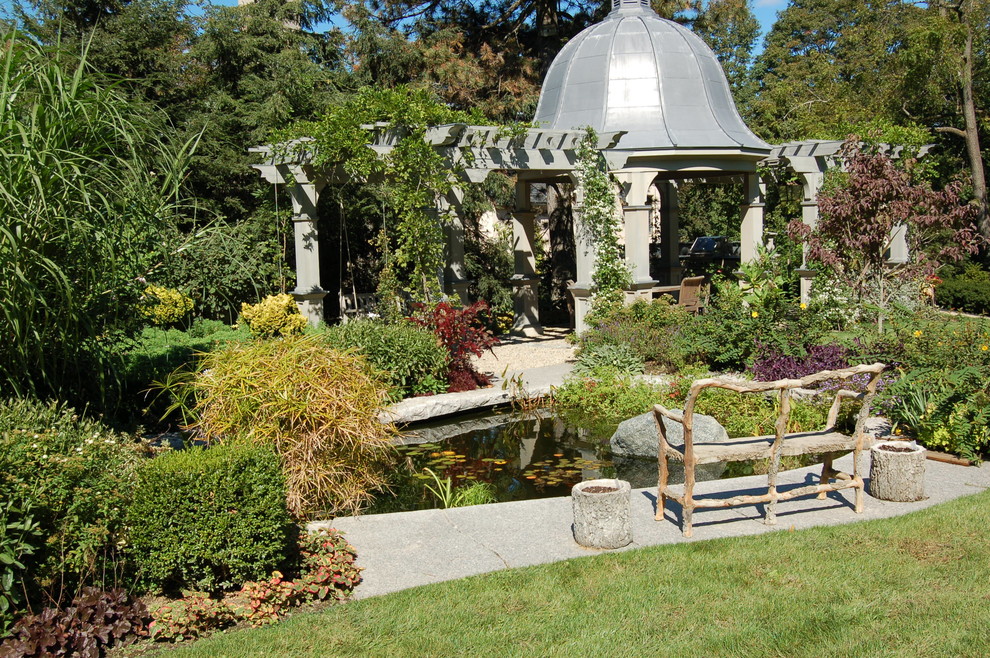 Modelo de jardín tradicional grande en verano en patio trasero con fuente, jardín francés, exposición parcial al sol y adoquines de piedra natural