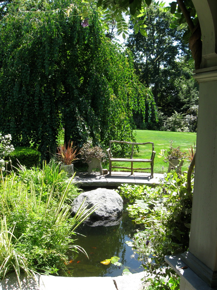 Bild på en stor vintage trädgård i delvis sol på sommaren, med en fontän och naturstensplattor