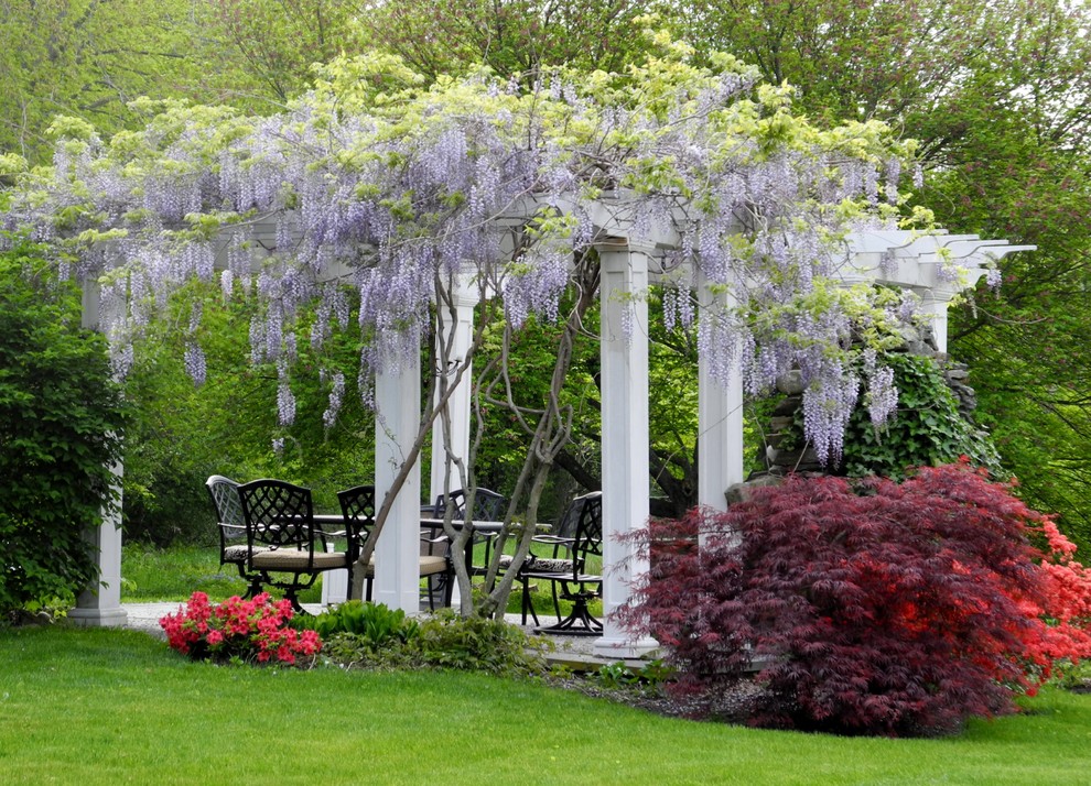 Cette photo montre un jardin avec pergola arrière chic au printemps et de taille moyenne avec une exposition ensoleillée et des pavés en pierre naturelle.