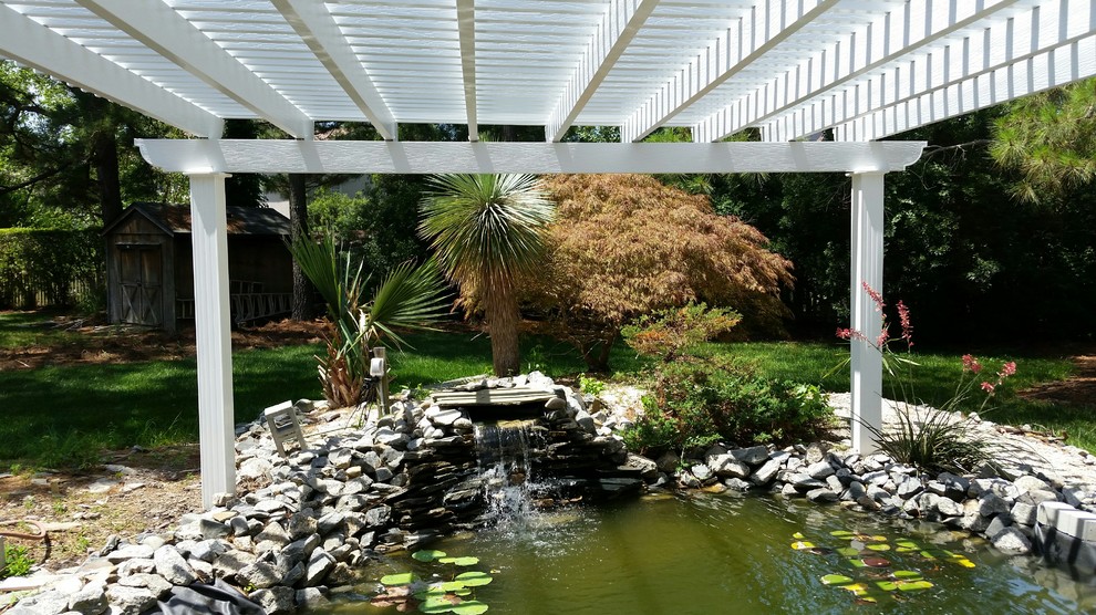 This is an example of a mid-sized tropical backyard stone pond in Other.