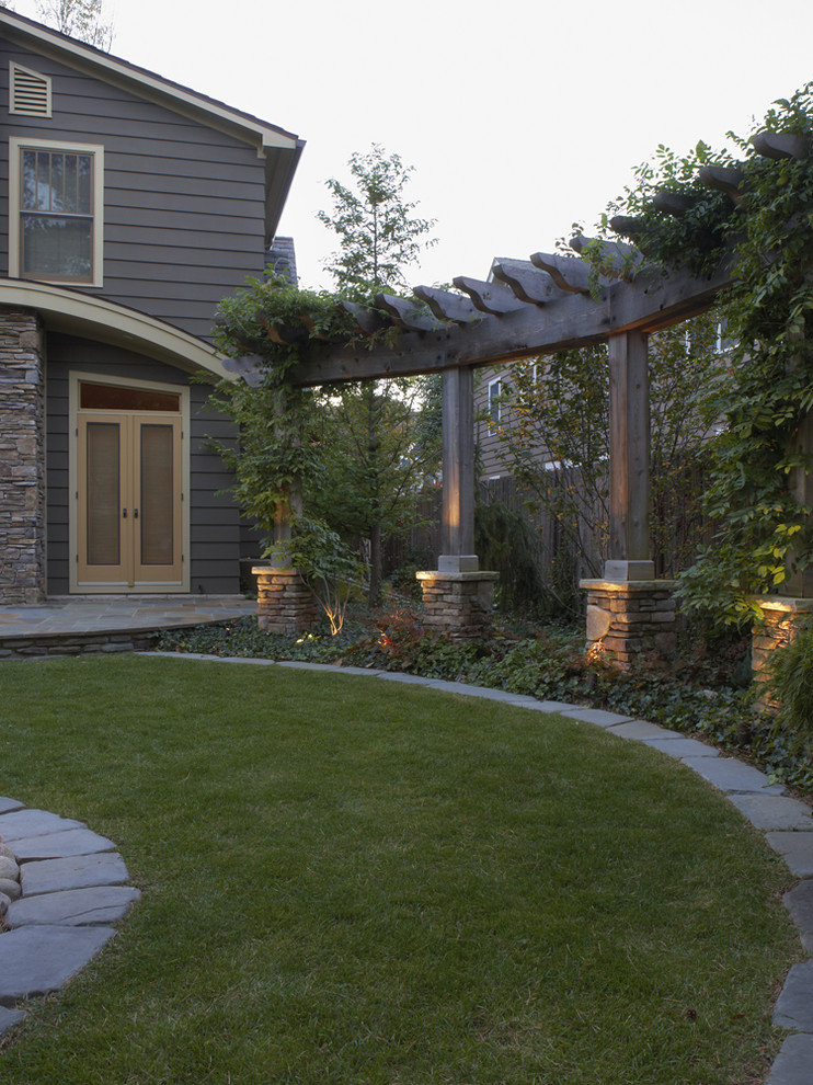 Design ideas for a mid-sized contemporary partial sun backyard stone lawn edging in Detroit with a pergola.