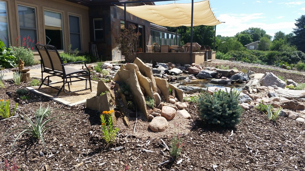Photo of an expansive sloped xeriscape full sun garden for summer in Denver with a water feature and gravel.
