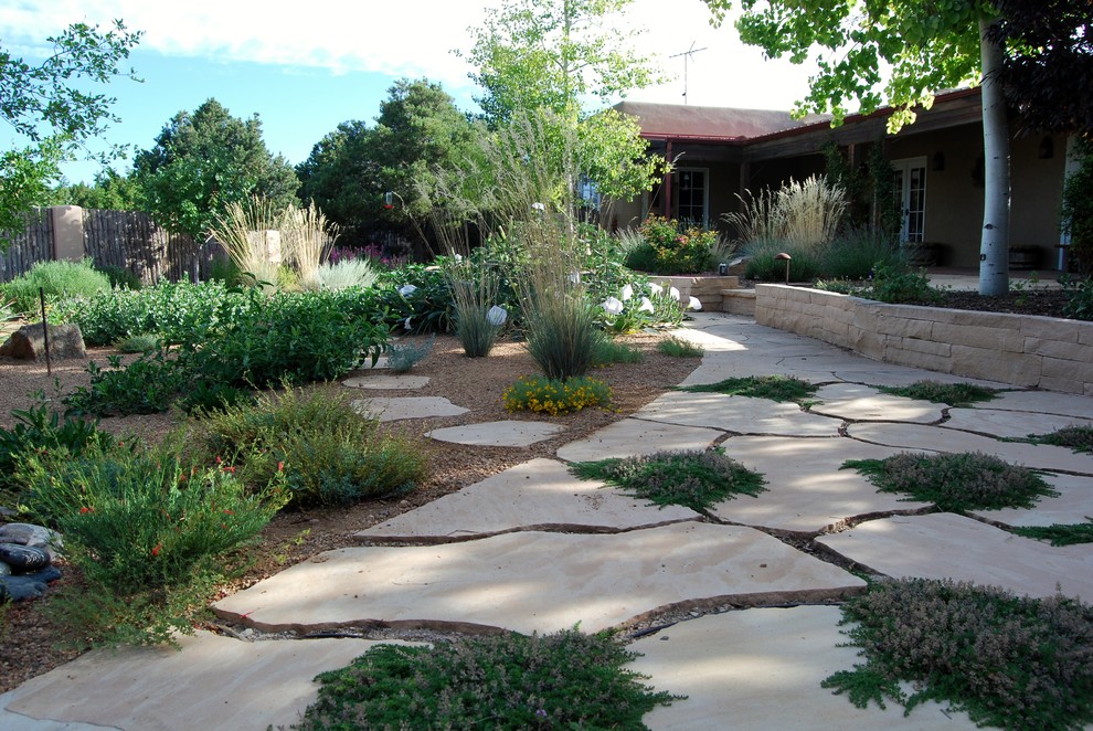 Ejemplo de jardín de secano mediterráneo de tamaño medio en verano en patio trasero con exposición parcial al sol y adoquines de piedra natural