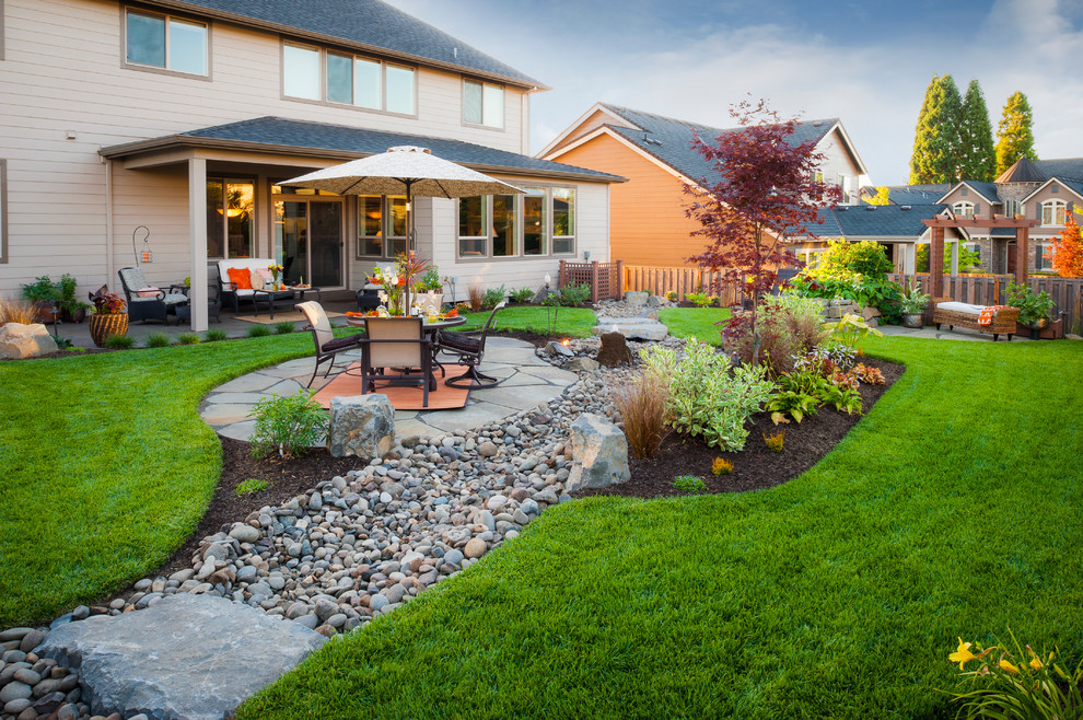 Photo of a traditional backyard river rock landscaping in Portland.