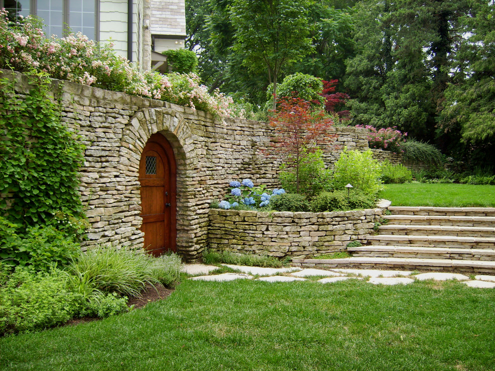 Esempio di un giardino tradizionale dietro casa con pavimentazioni in pietra naturale e scale