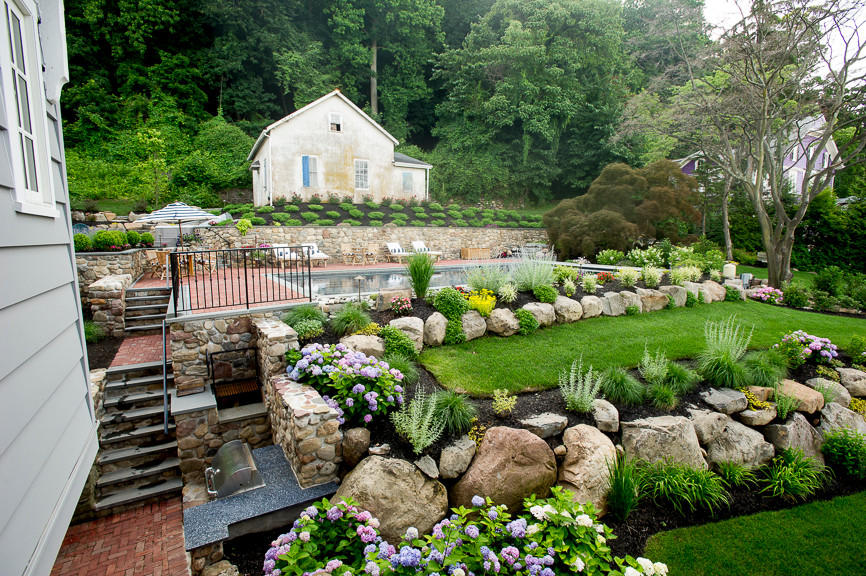 Cette photo montre un jardin arrière chic avec un mur de soutènement et des pavés en pierre naturelle.
