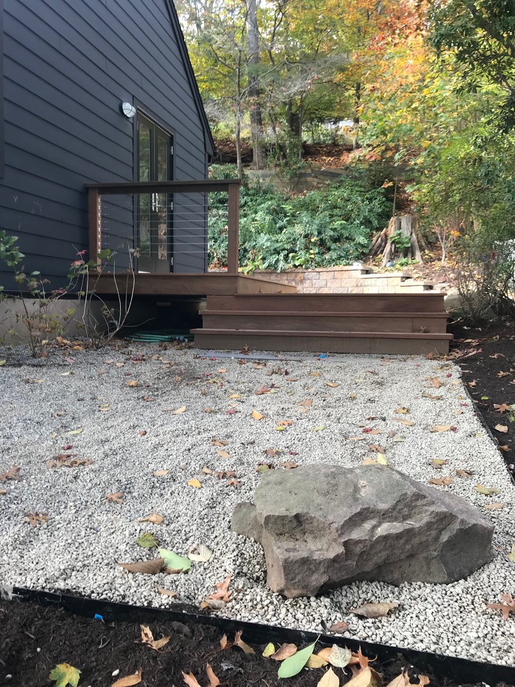 Small scandi front xeriscape fully shaded garden for autumn in New York with a retaining wall and gravel.