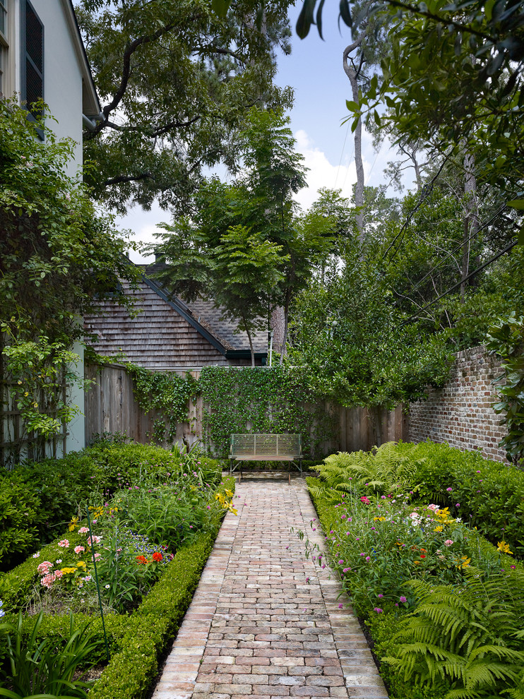 Immagine di un giardino tradizionale esposto a mezz'ombra dietro casa in primavera con un ingresso o sentiero e pavimentazioni in mattoni