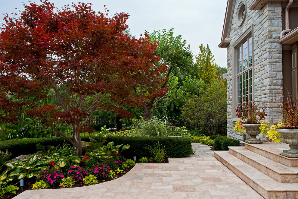 Idéer för en klassisk trädgård framför huset och blomsterrabatt, med naturstensplattor
