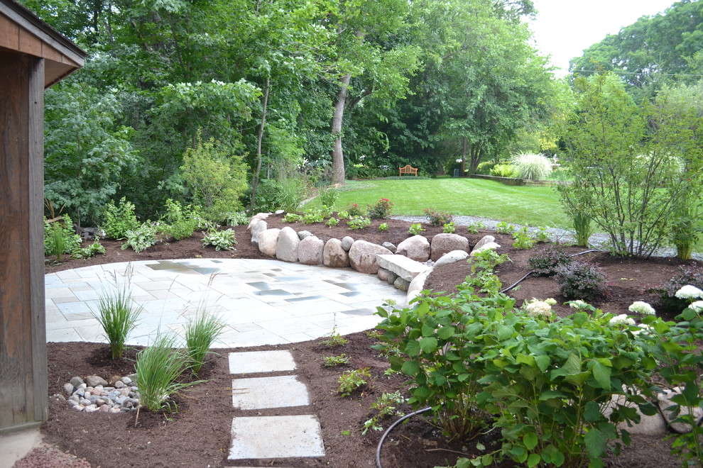 Design ideas for a mid-sized rustic backyard stone landscaping in Milwaukee.