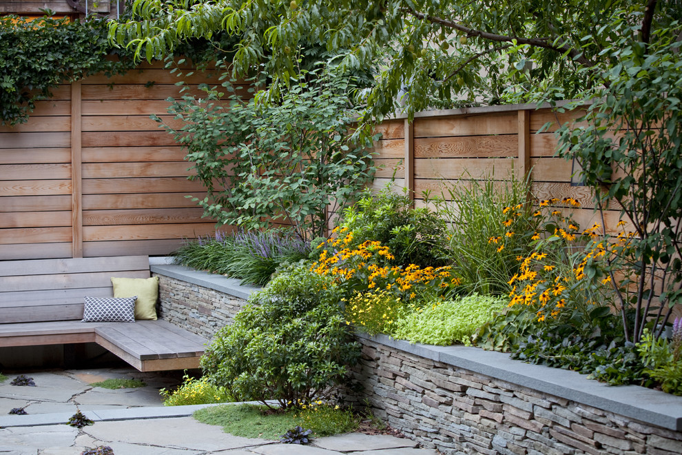 Foto di un giardino moderno esposto a mezz'ombra di medie dimensioni e dietro casa in estate con un muro di contenimento e pavimentazioni in pietra naturale