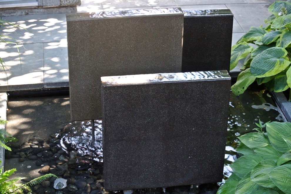 This is an example of a small modern partial sun garden in Vancouver with a water feature and concrete paving.