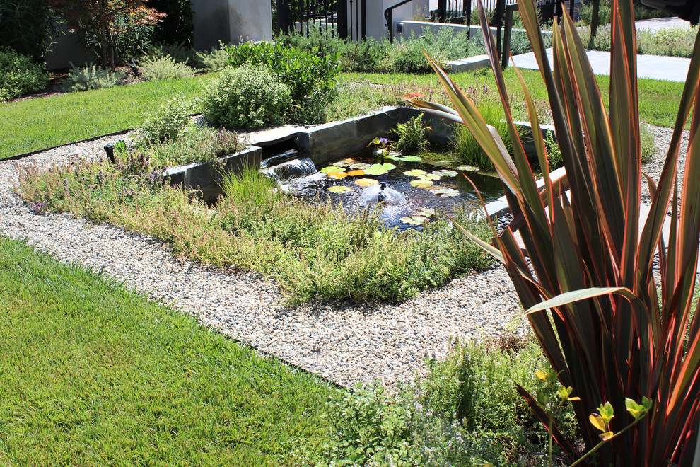 Foto på en mellanstor medelhavsstil trädgård framför huset, med en damm och naturstensplattor