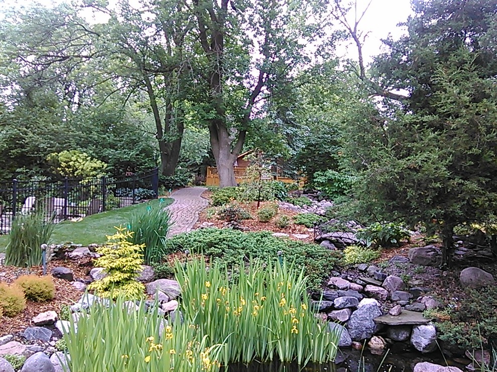 Inspiration for a medium sized rustic sloped xeriscape fully shaded garden for winter in Chicago with a water feature and mulch.