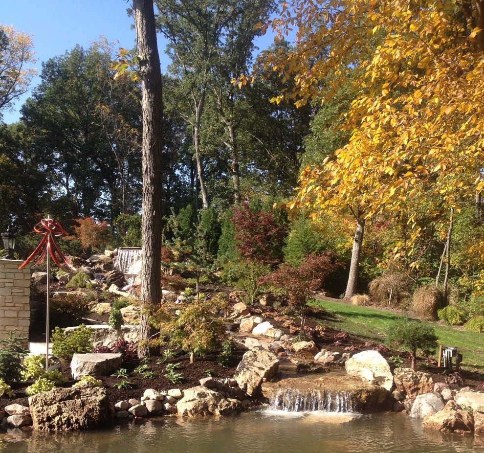 На фото: большой осенний участок и сад на заднем дворе в классическом стиле с полуденной тенью и покрытием из каменной брусчатки с