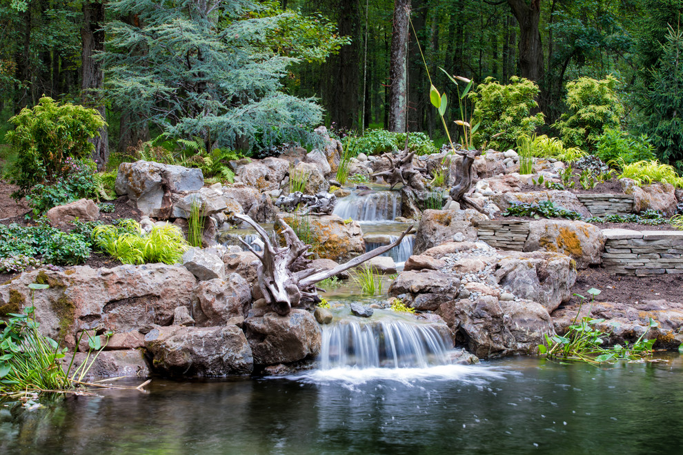 Aménagement d'un grand jardin arrière montagne avec un bassin et des pavés en pierre naturelle.