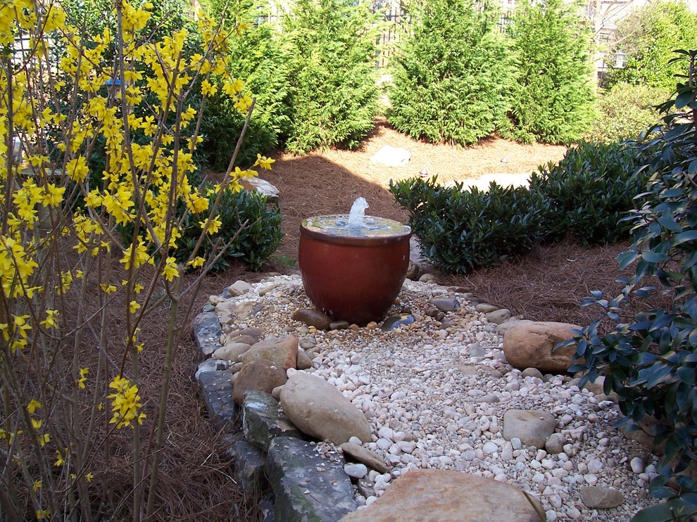 Photo of a large classic back formal fully shaded garden in Atlanta with a water feature and gravel.
