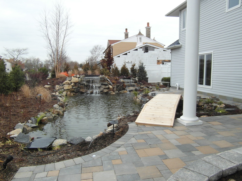 Medium sized beach style back partial sun garden for summer in New York with a water feature and concrete paving.