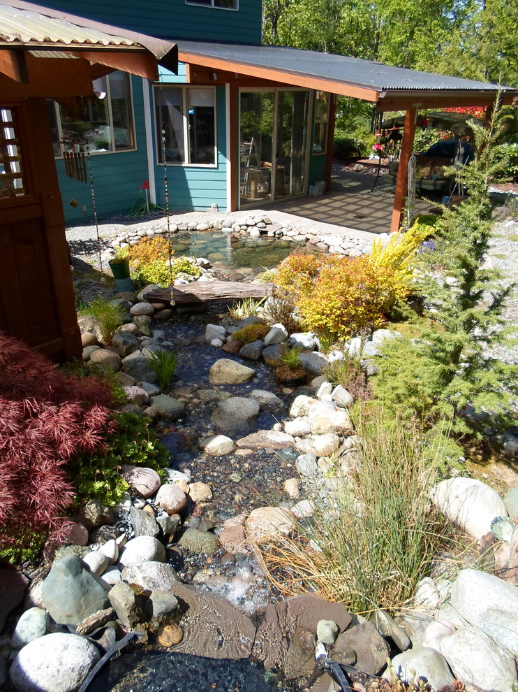 Ejemplo de jardín tradicional de tamaño medio en verano en patio trasero con fuente y exposición total al sol