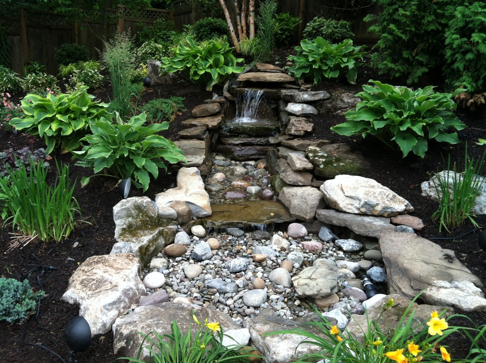 Mittelgroßer, Halbschattiger Asiatischer Gartenwasserfall im Frühling, hinter dem Haus mit Natursteinplatten in New York