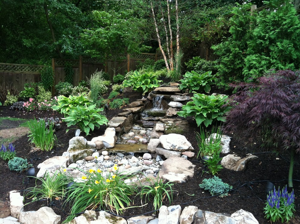 This is an example of a mid-sized asian partial sun backyard stone pond in New York for spring.