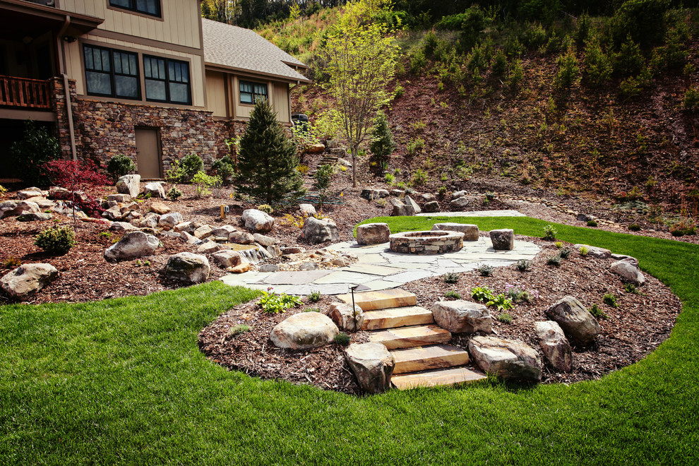 This is an example of a mid-sized traditional full sun backyard stone landscaping in Charlotte with a fire pit.