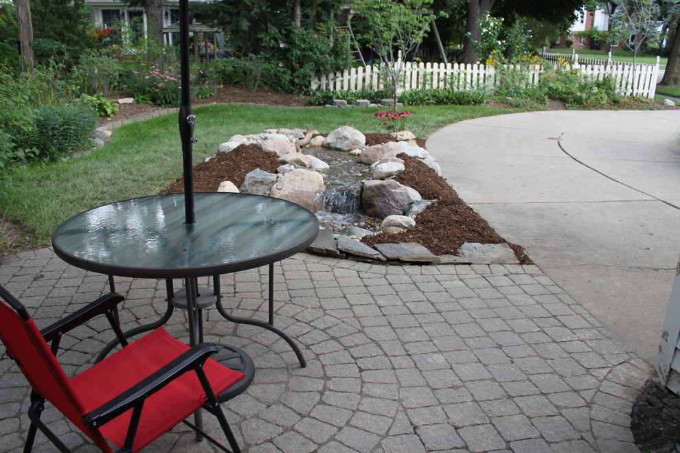 Photo of a medium sized traditional side driveway full sun garden for summer in Detroit with a water feature and mulch.