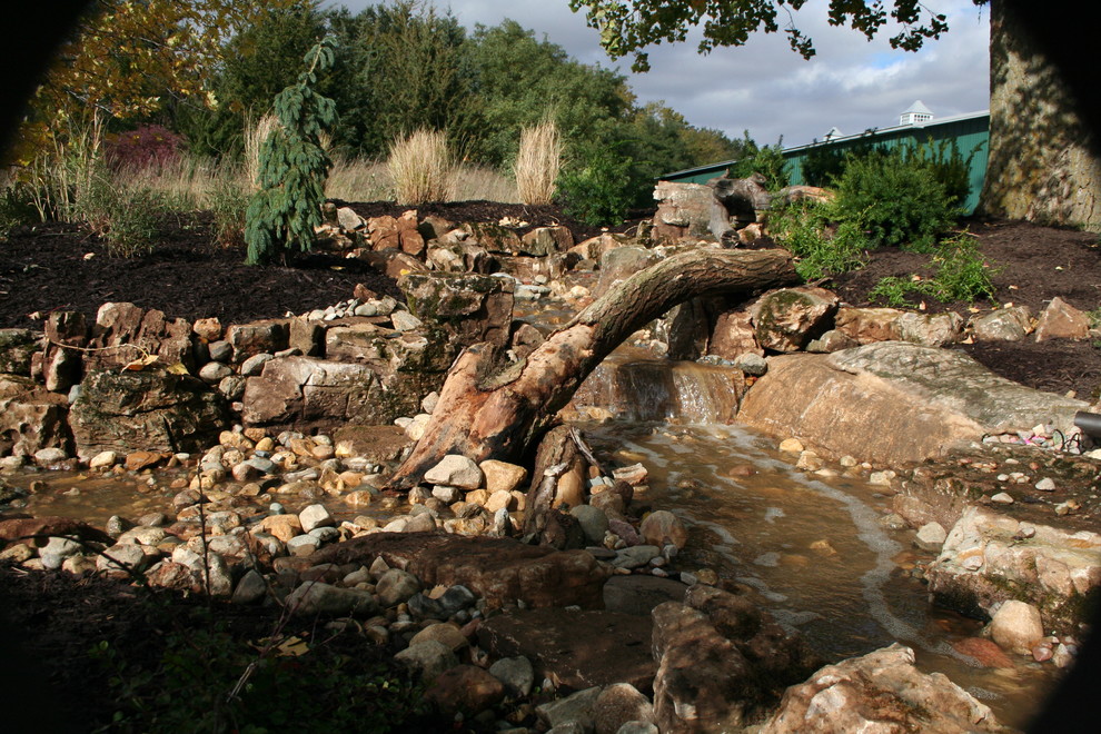 Foto di un grande giardino stile rurale esposto in pieno sole in inverno con fontane, un pendio, una collina o una riva e pavimentazioni in pietra naturale