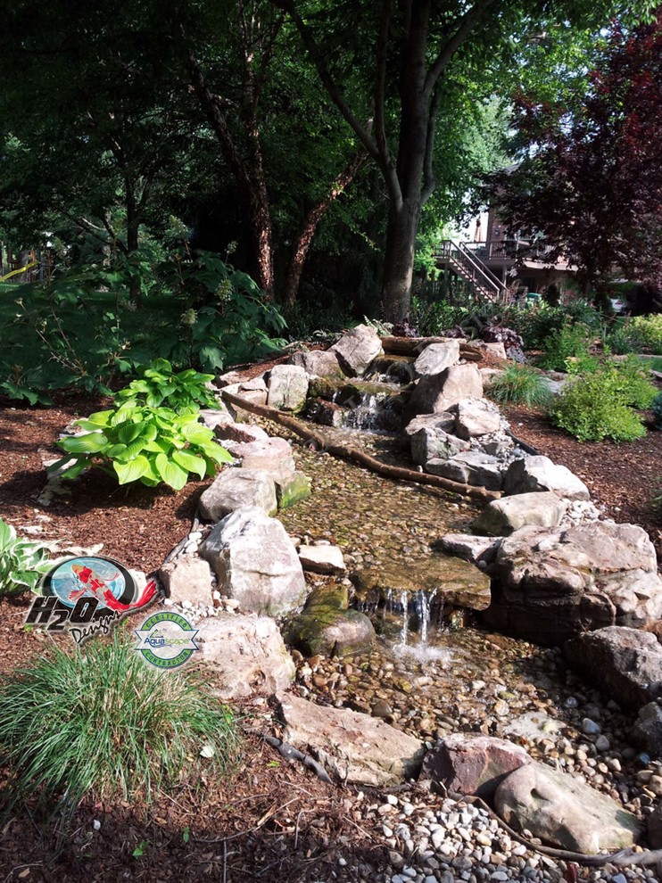 Photo of a large eclectic partial sun backyard mulch water fountain landscape in Louisville.
