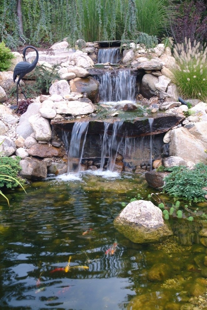 Photo of a tropical drought-tolerant and full sun hillside stone pond in New York for summer.
