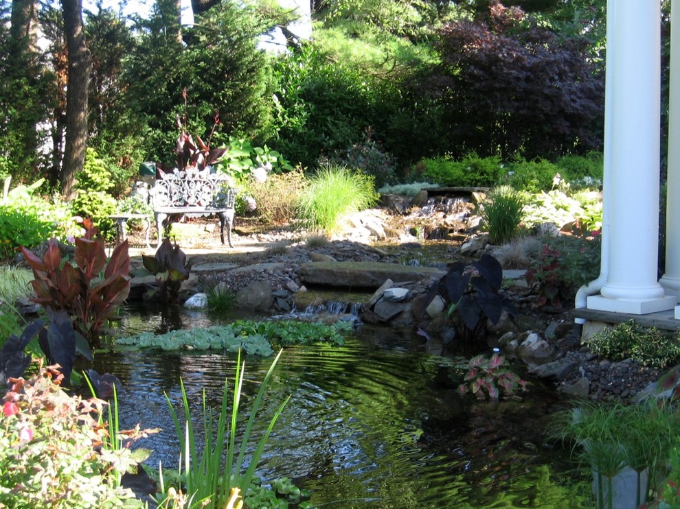 Inspiration for a world-inspired sloped xeriscape full sun garden for summer in New York with a pond and natural stone paving.